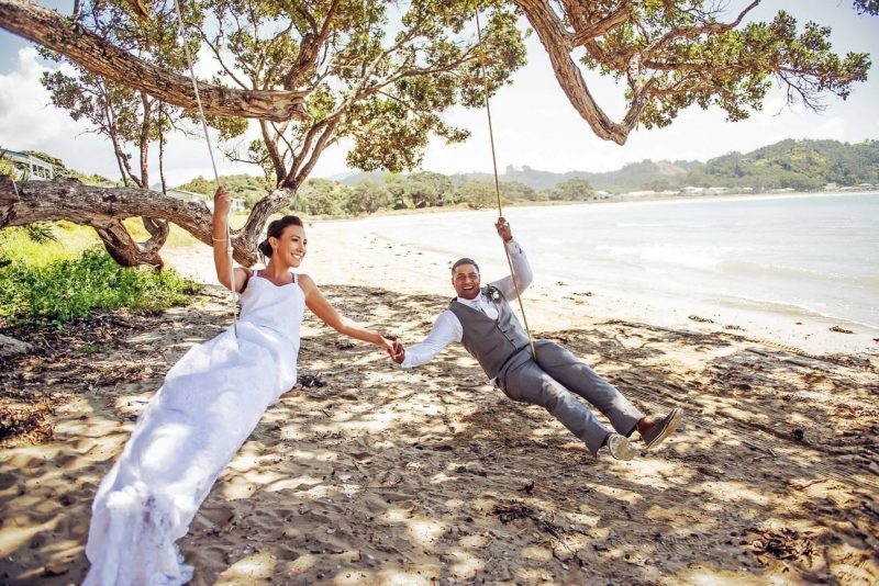 A newly wed couple playing swing on the shore