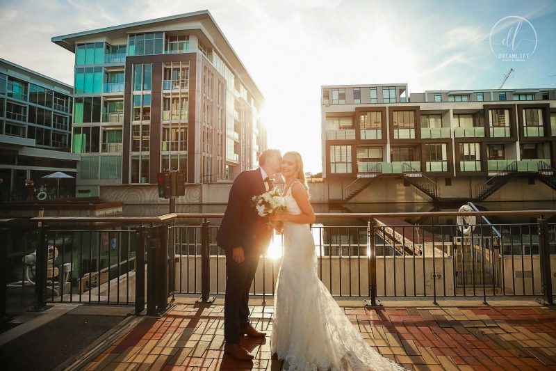 bride and groom in a sunset and city building backdrop