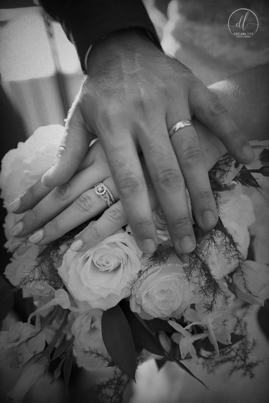 two hands with wedding ring holding a flower boquet