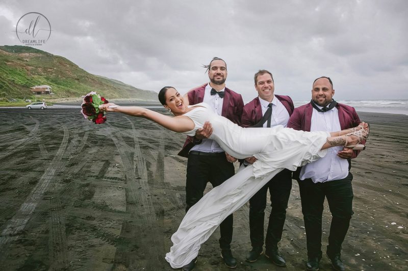 groom and his groomsmen lifting his bride while holding a flower bouquet