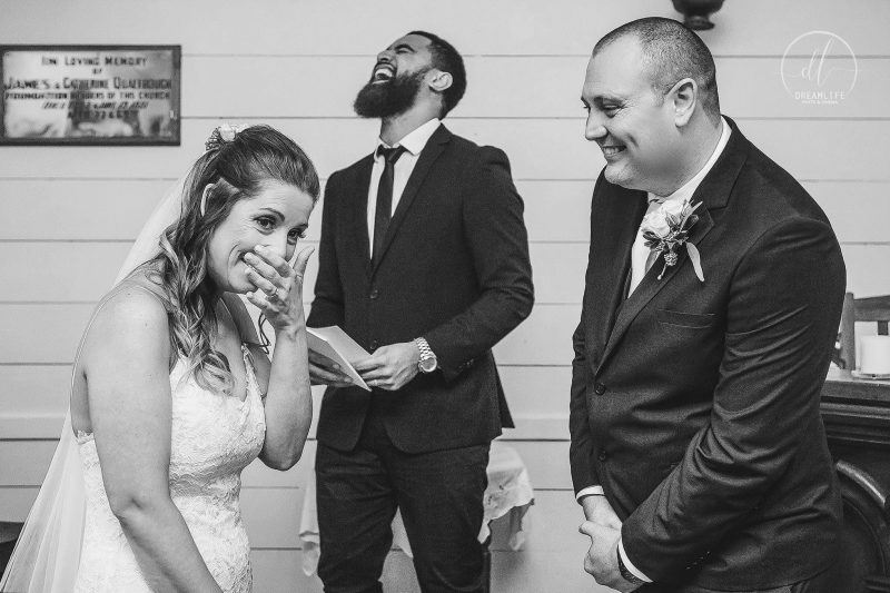 bride and groom laughing in front of a pastor on their wedding ceremony