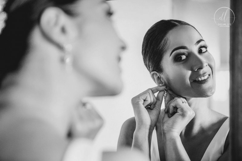 bride in front of a mirror fixing her earring