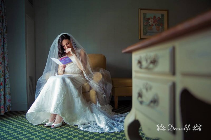 bride holding a book beside a cabinet