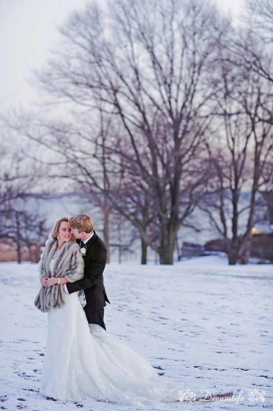 bride and groom in a snow with tree backdrop