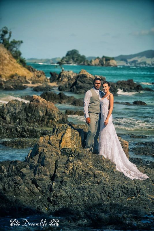 groom and bride standing in a beach rock