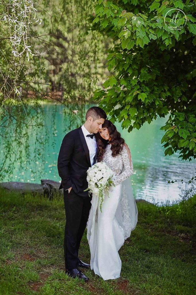 bride and groom in a lakeside backdrop with trees