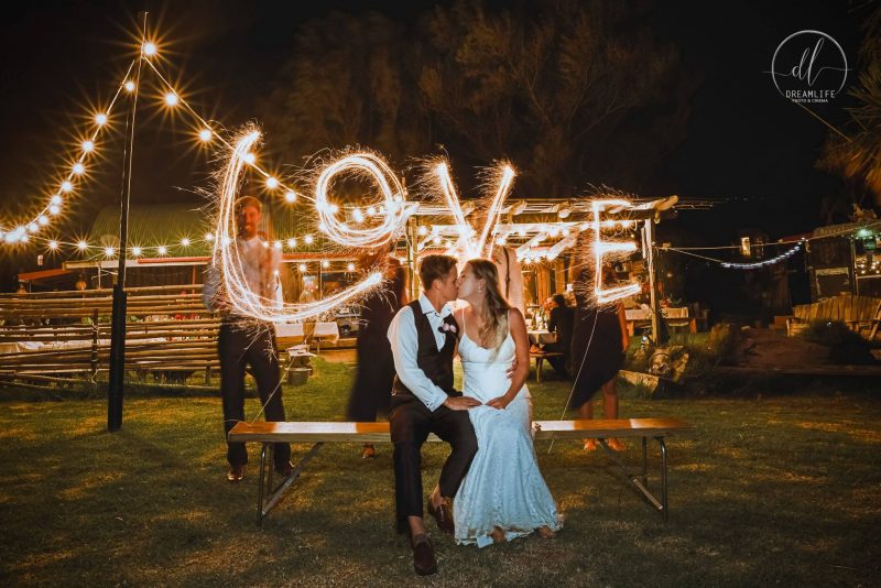 bride and groom with love spelled firecracker backdrop