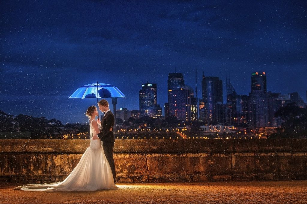 bride and groom holding an umbrella in a night sky backdrop