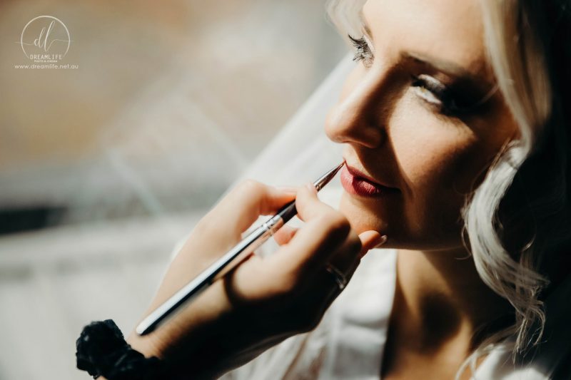 applying lipstick to a bride