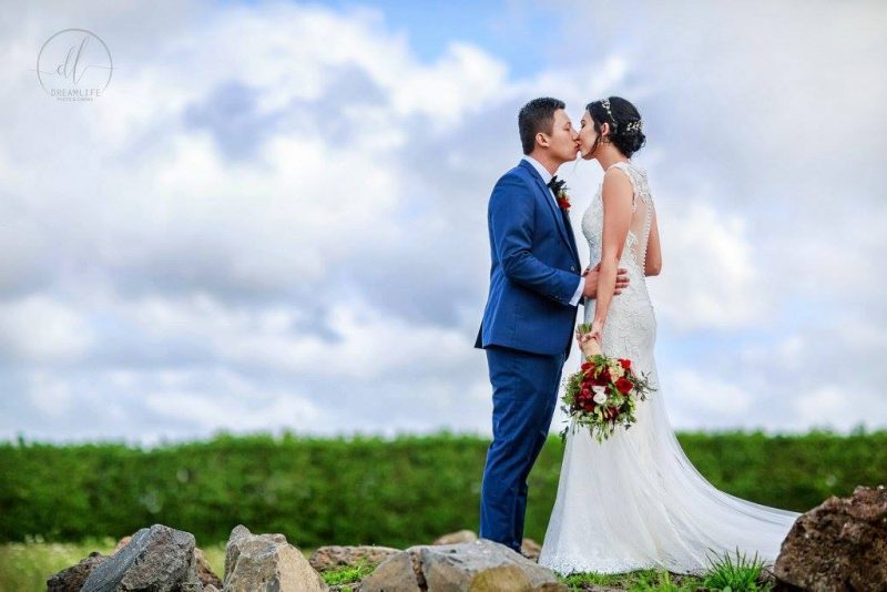 groom kissing his bride in a scenic open field