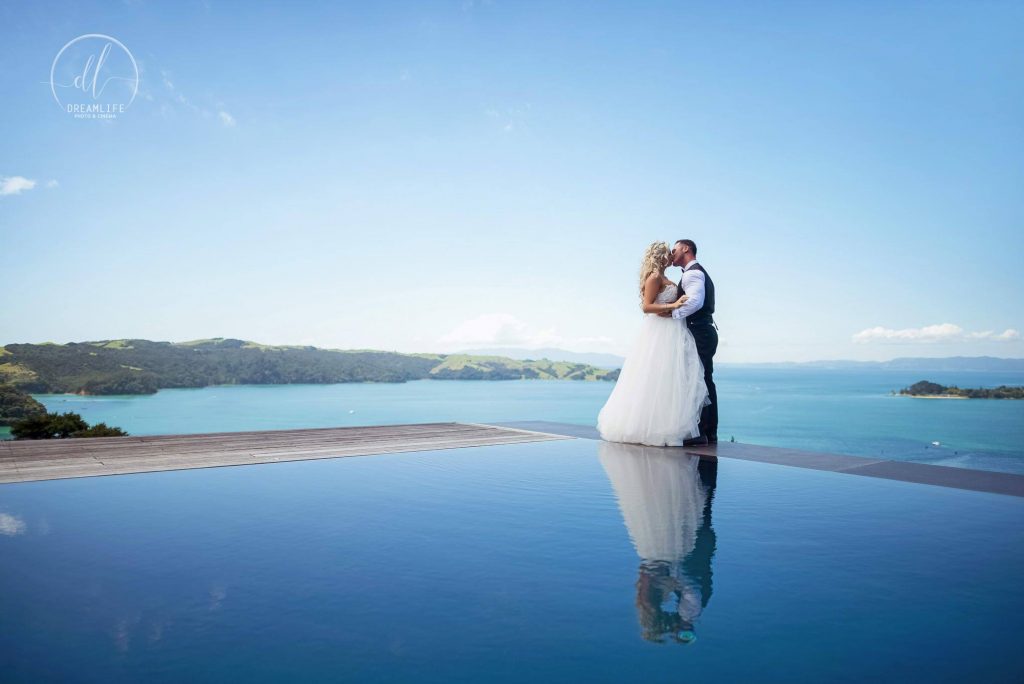bride and groom in an infinity pool with open sea backdrop